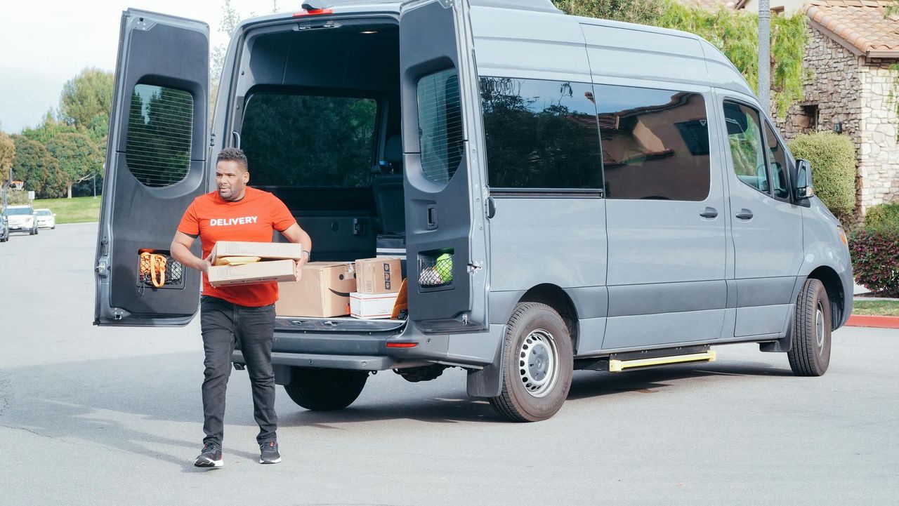 van with rear doors open and male delivering parcels